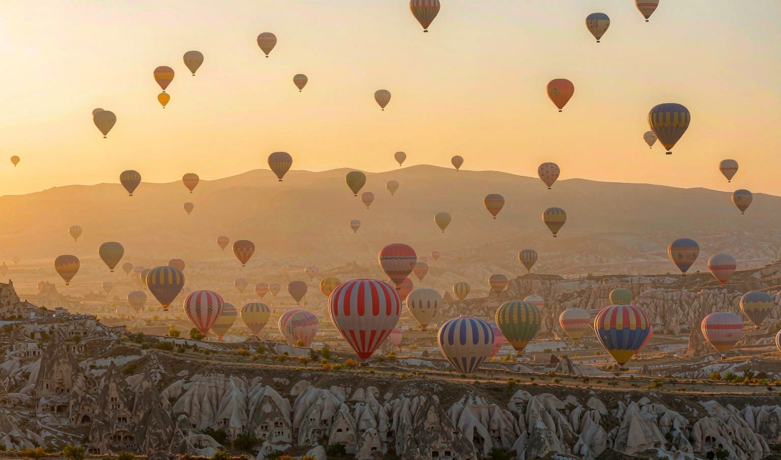 Hot air balloons drifting over the fairy chimneys of Cappadocia at sunrise